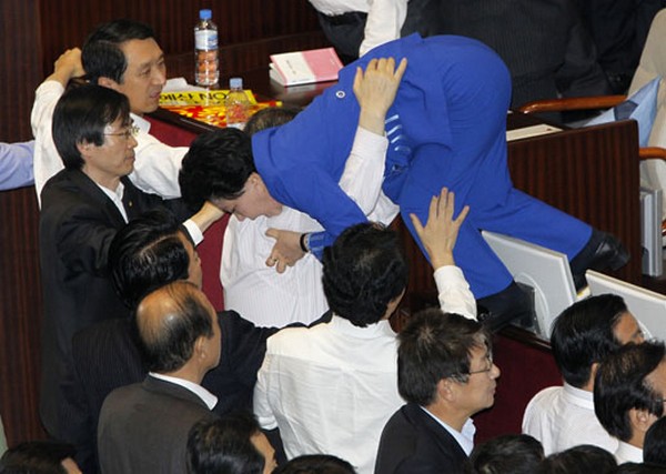 Lawmakers of opposition parties help their fellow lawmaker who tries to escape as they scuffle with lawmakers of GNP at National Assembly plenary session hall in Seoul